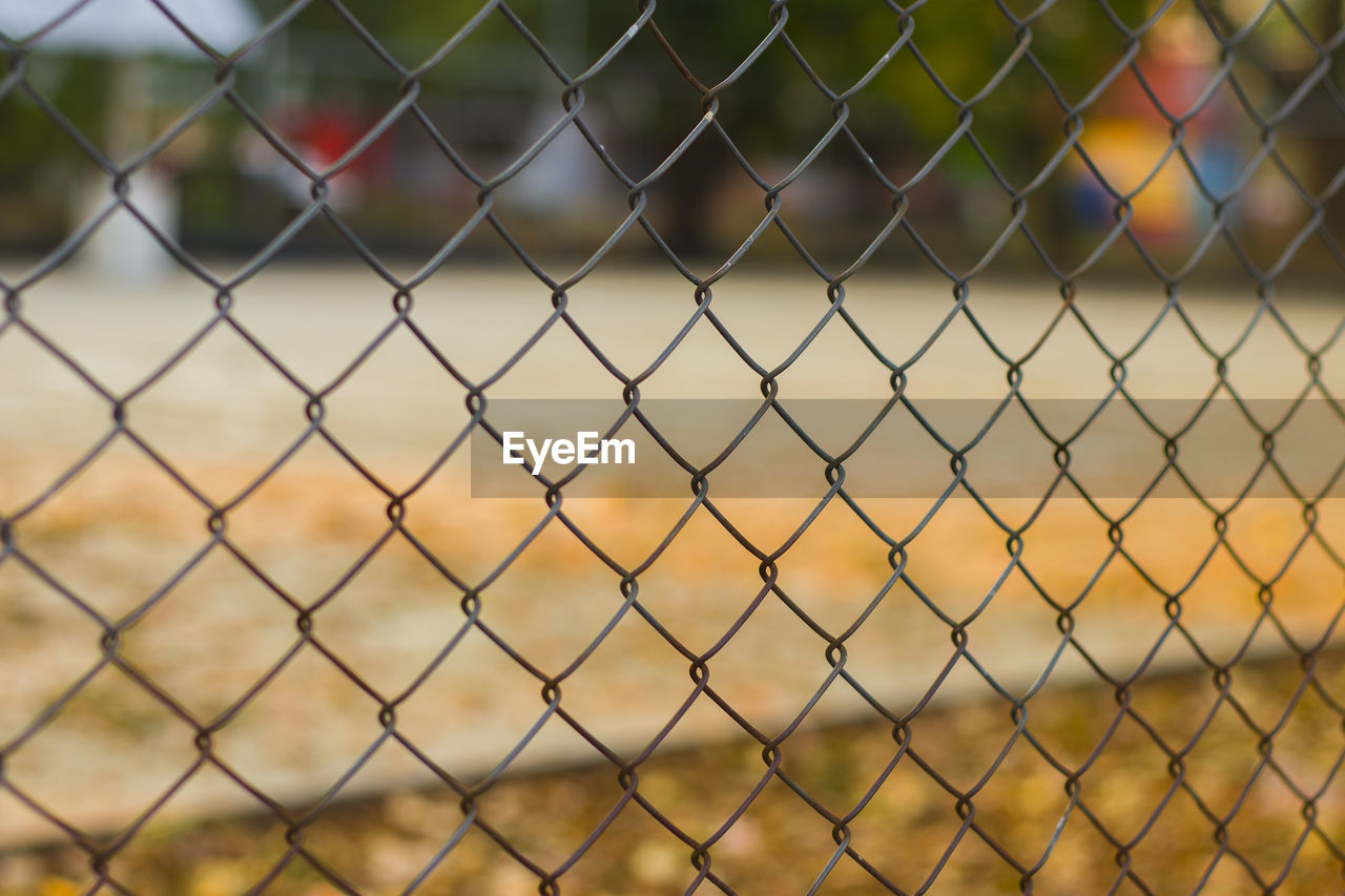 Close-up of chainlink fence against playground