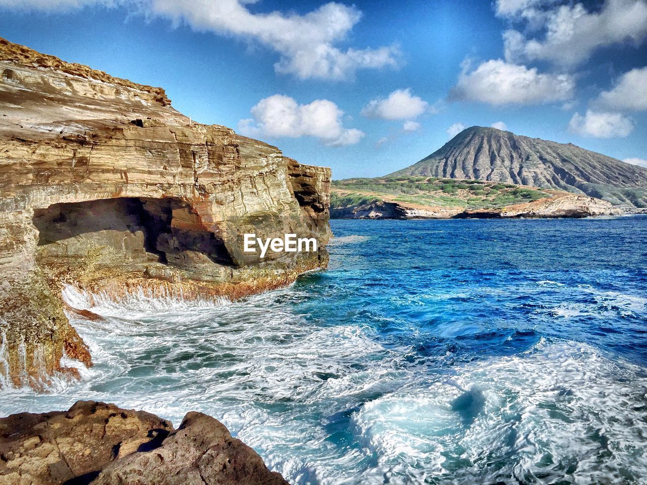 VIEW OF SEA AND MOUNTAIN AGAINST CLOUDY SKY