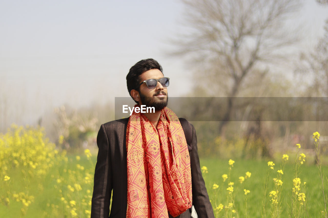 Young man looking away while standing on field