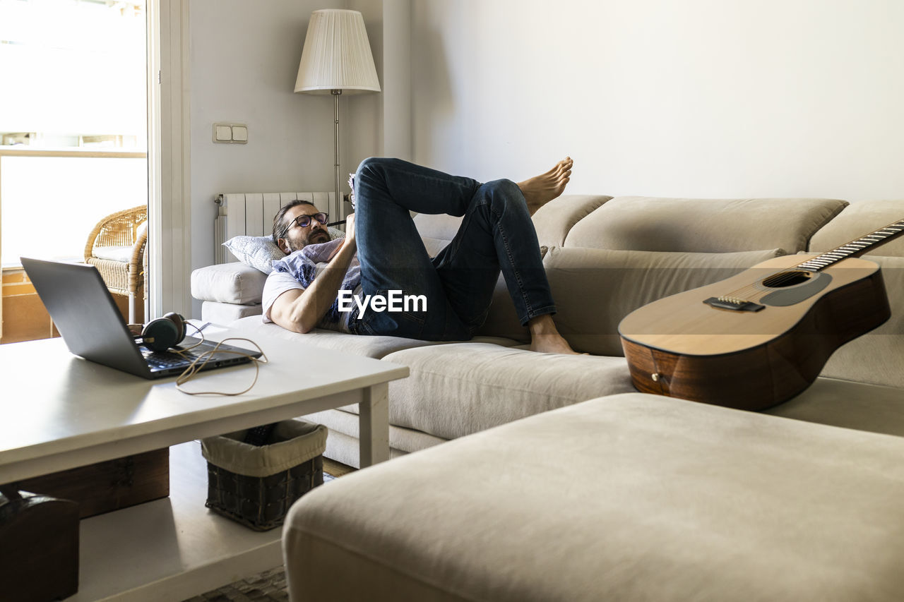 Man writing notes on couch in cozy living room