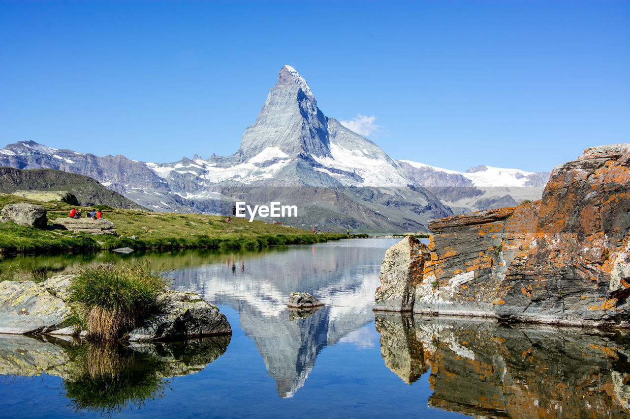 Scenic view of lake and mountains against blue sky