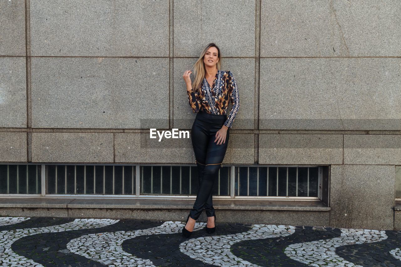 Portrait of woman standing against building