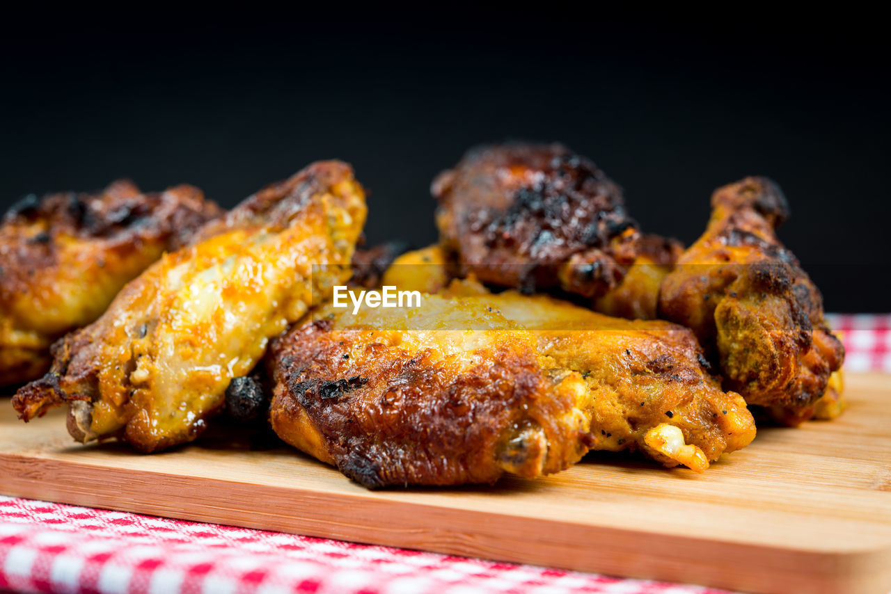 Close-up of fried chicken wings on cutting board against black background