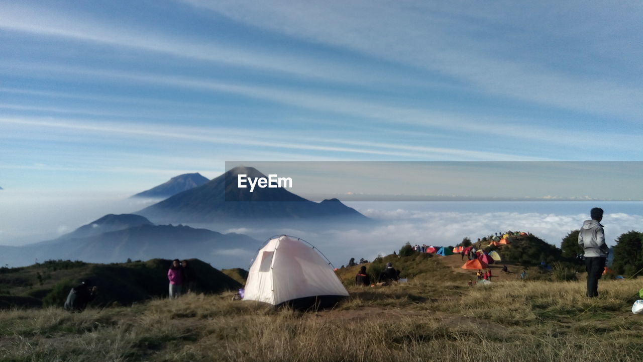 People camping on mountain against sky
