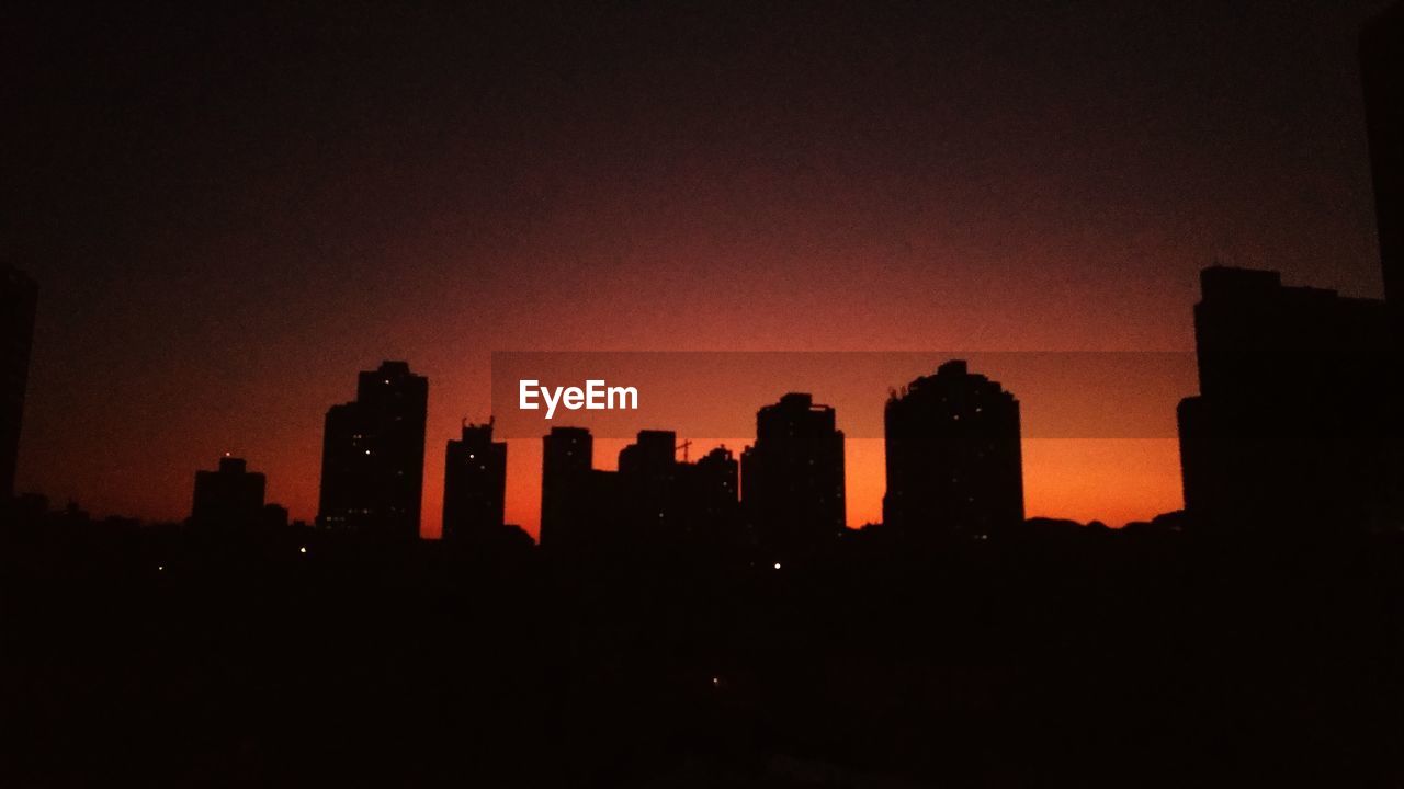 SILHOUETTE BUILDINGS IN CITY AGAINST SKY AT NIGHT