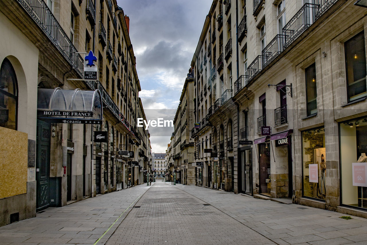 NARROW STREET AMIDST BUILDINGS AGAINST SKY