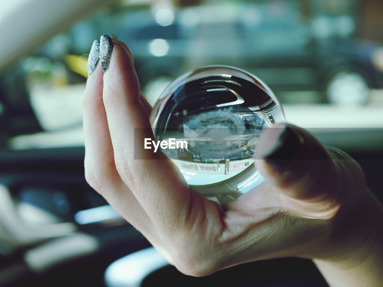 Close-up of hand holding glass with reflection