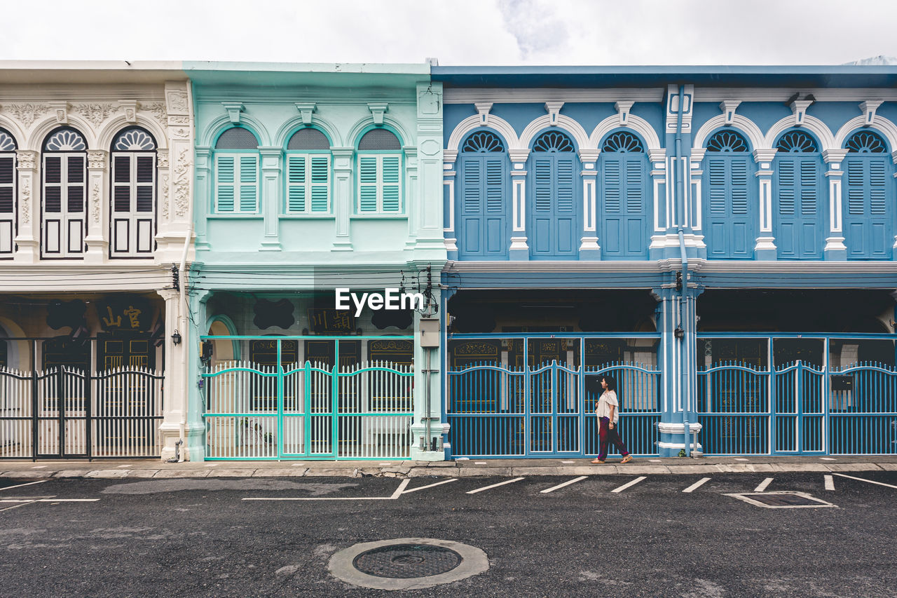 REAR VIEW OF WOMAN STANDING BY BUILDING IN CITY