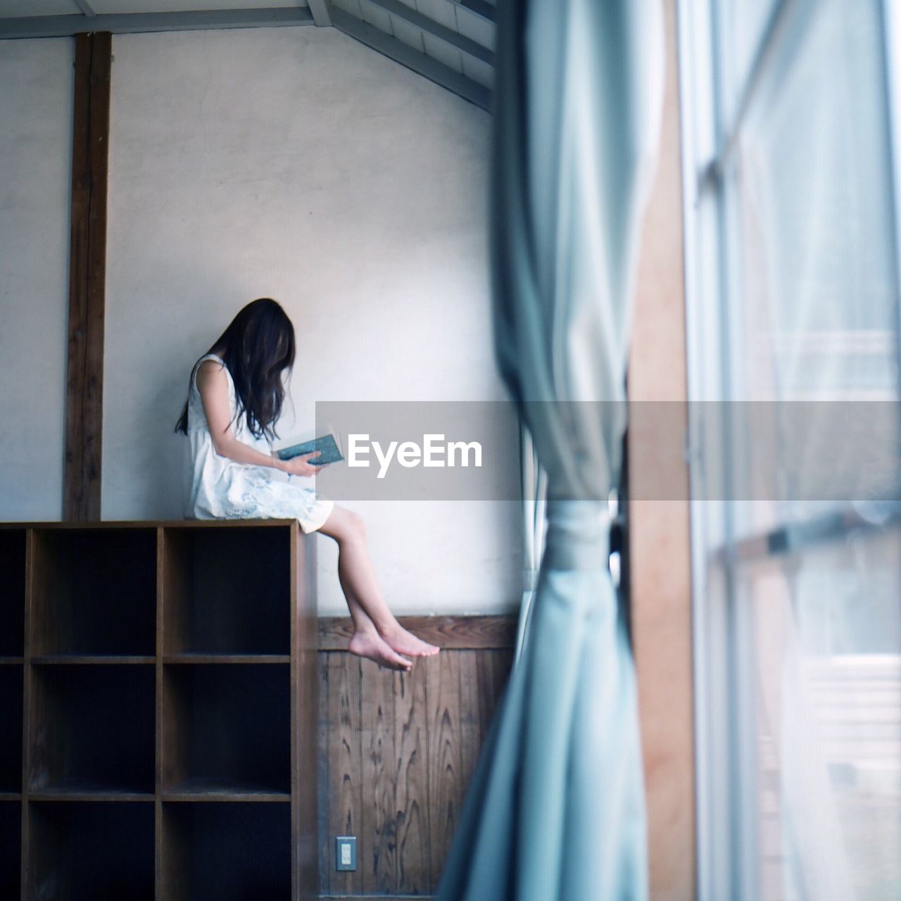 Girl sitting on shelf and reading a book