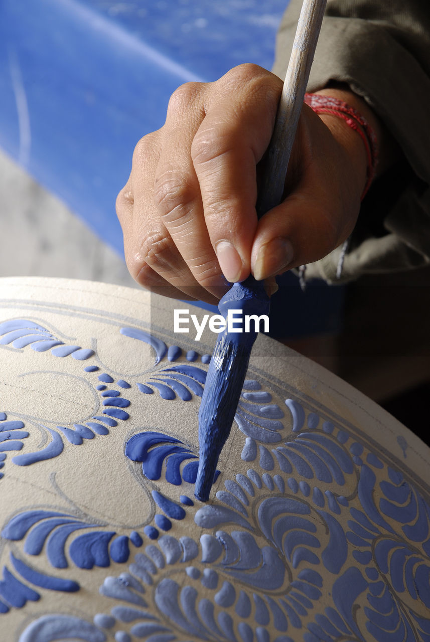 Cropped hands of craftsperson making clay product in pottery workshop