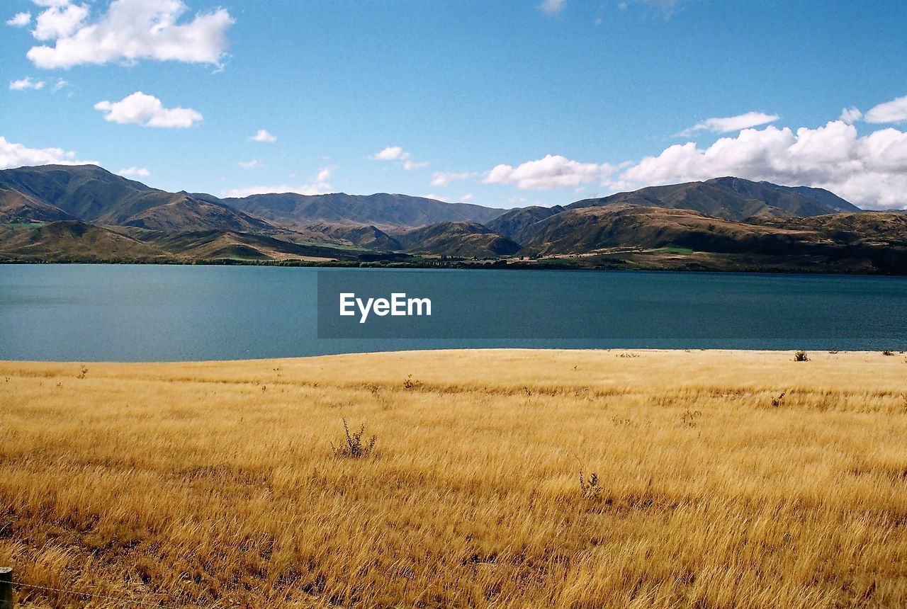 SCENIC VIEW OF LAKE BY MOUNTAIN AGAINST SKY