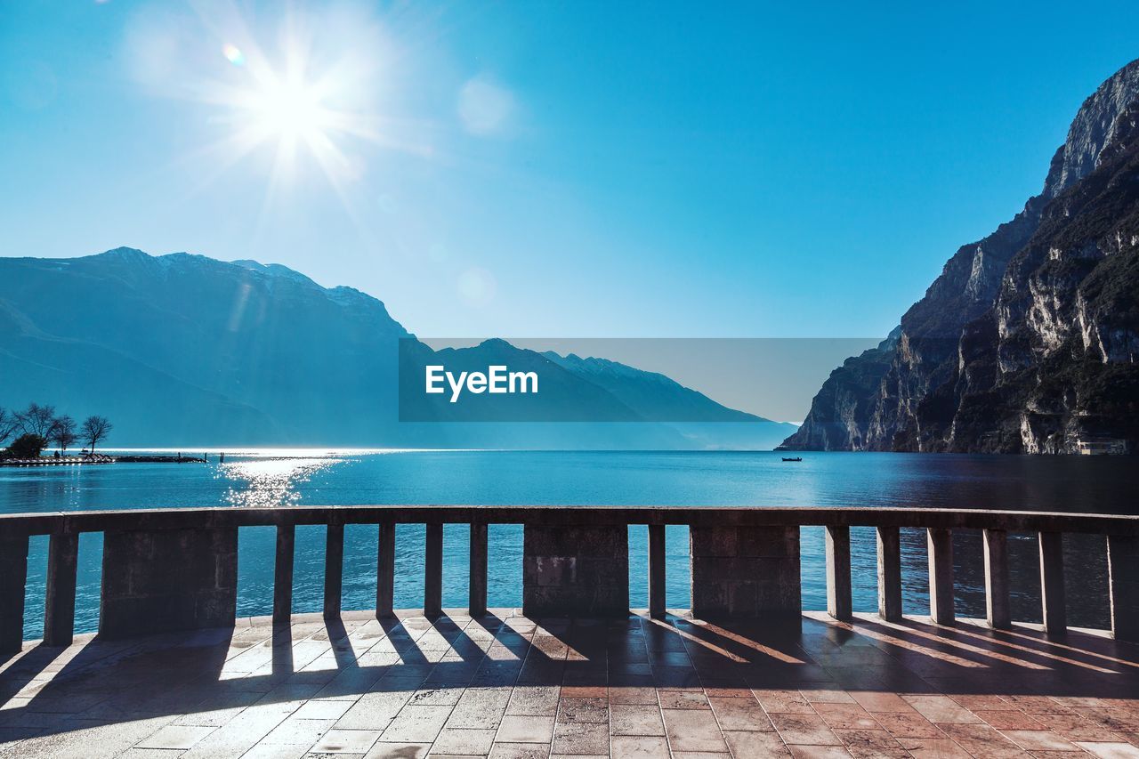 Scenic view of lake garda against mountains on sunny day