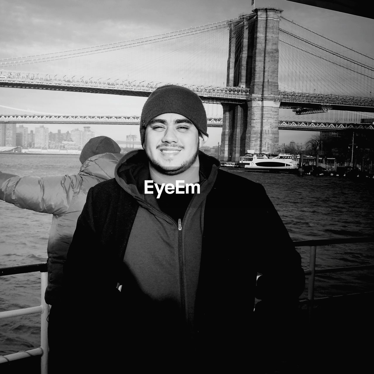 Portrait of smiling man standing against brooklyn bridge