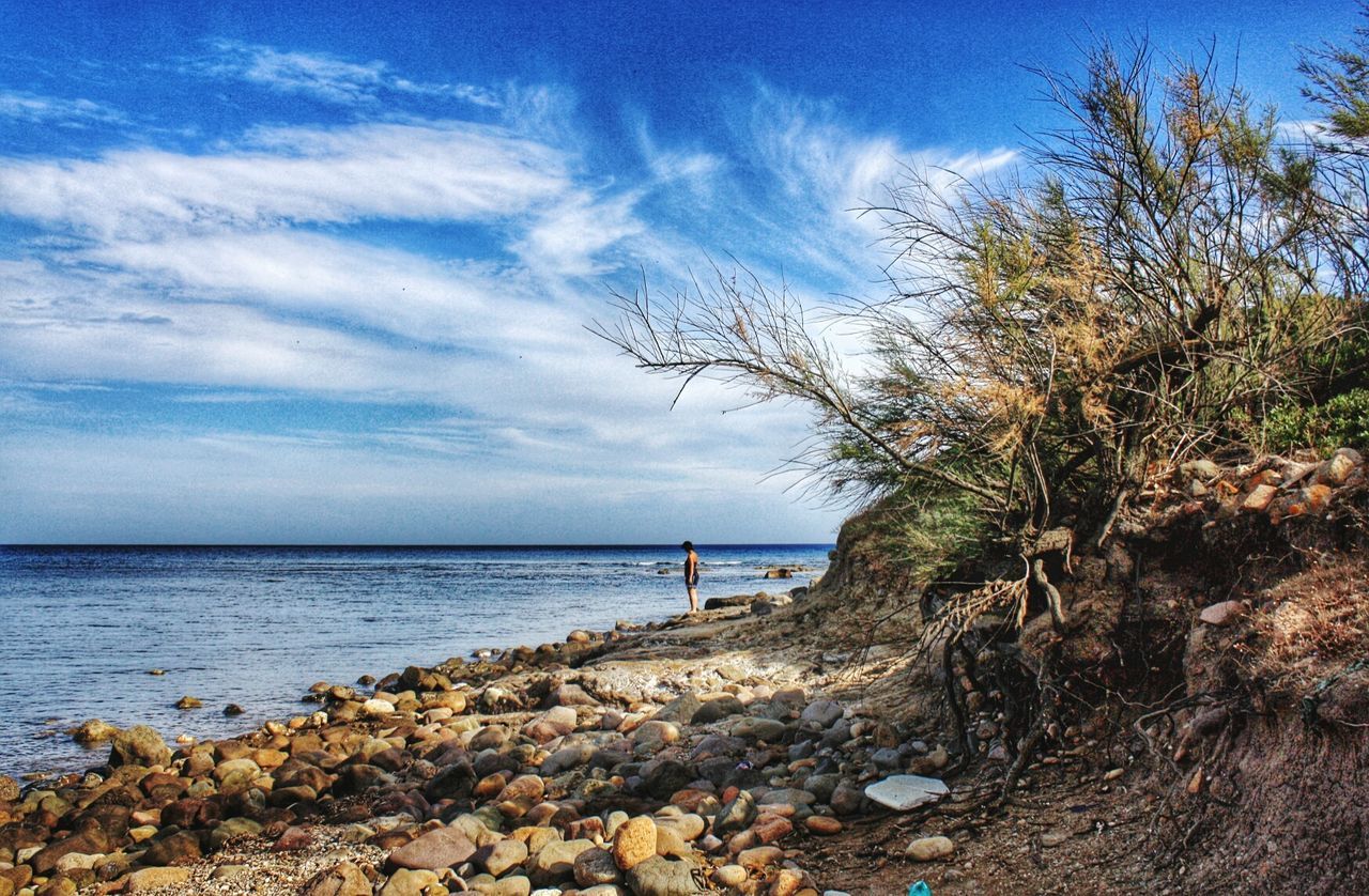 Distant view of woman standing at sea shore