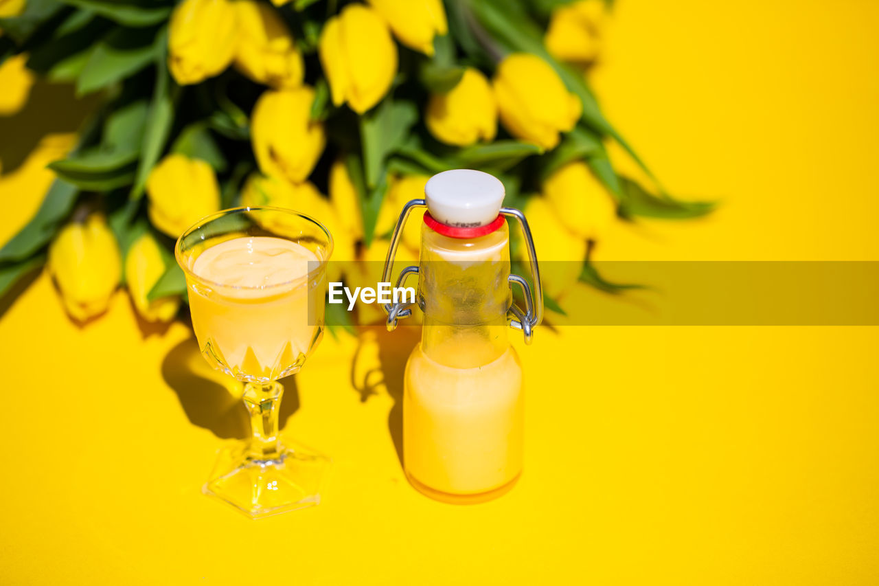 CLOSE-UP OF DRINK ON GLASS WITH YELLOW TABLE