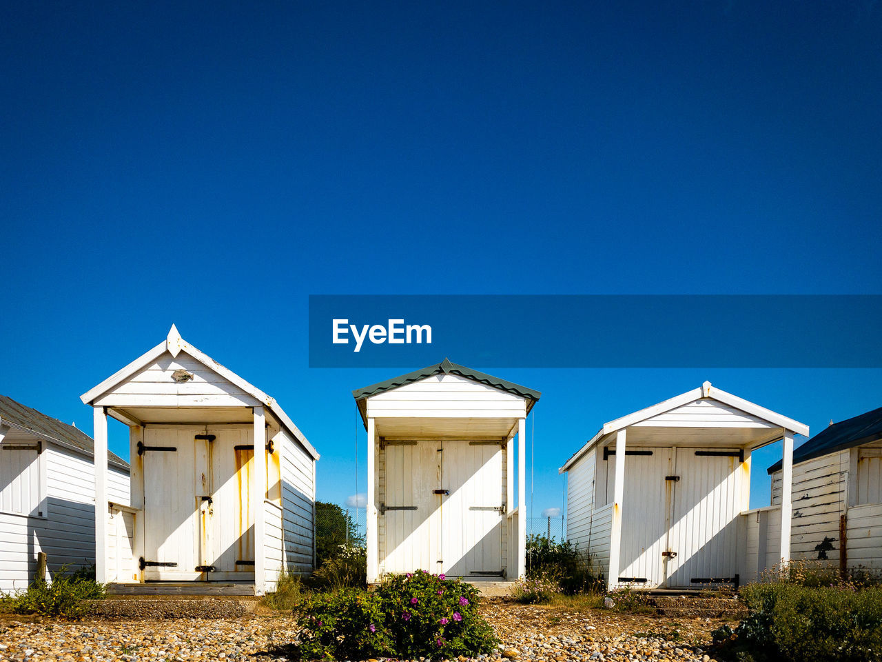 Low angle view of beach huts against clear blue sky