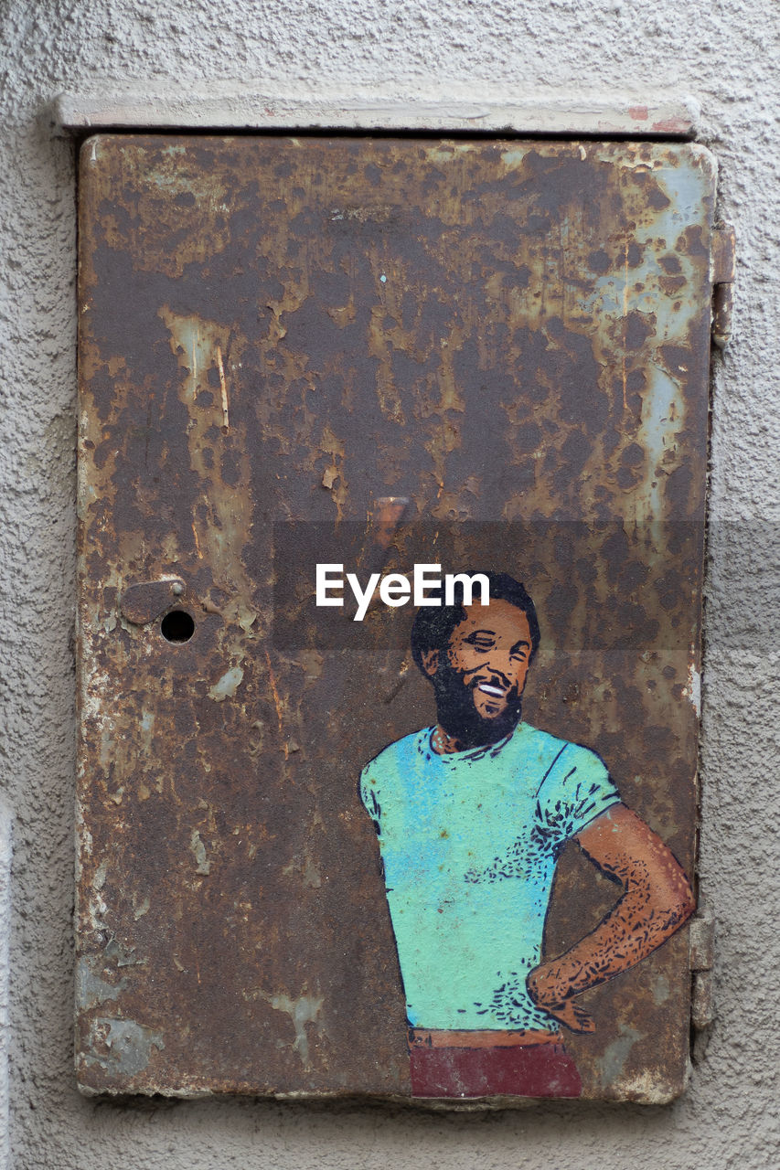 PORTRAIT OF YOUNG MAN AGAINST METAL WALL