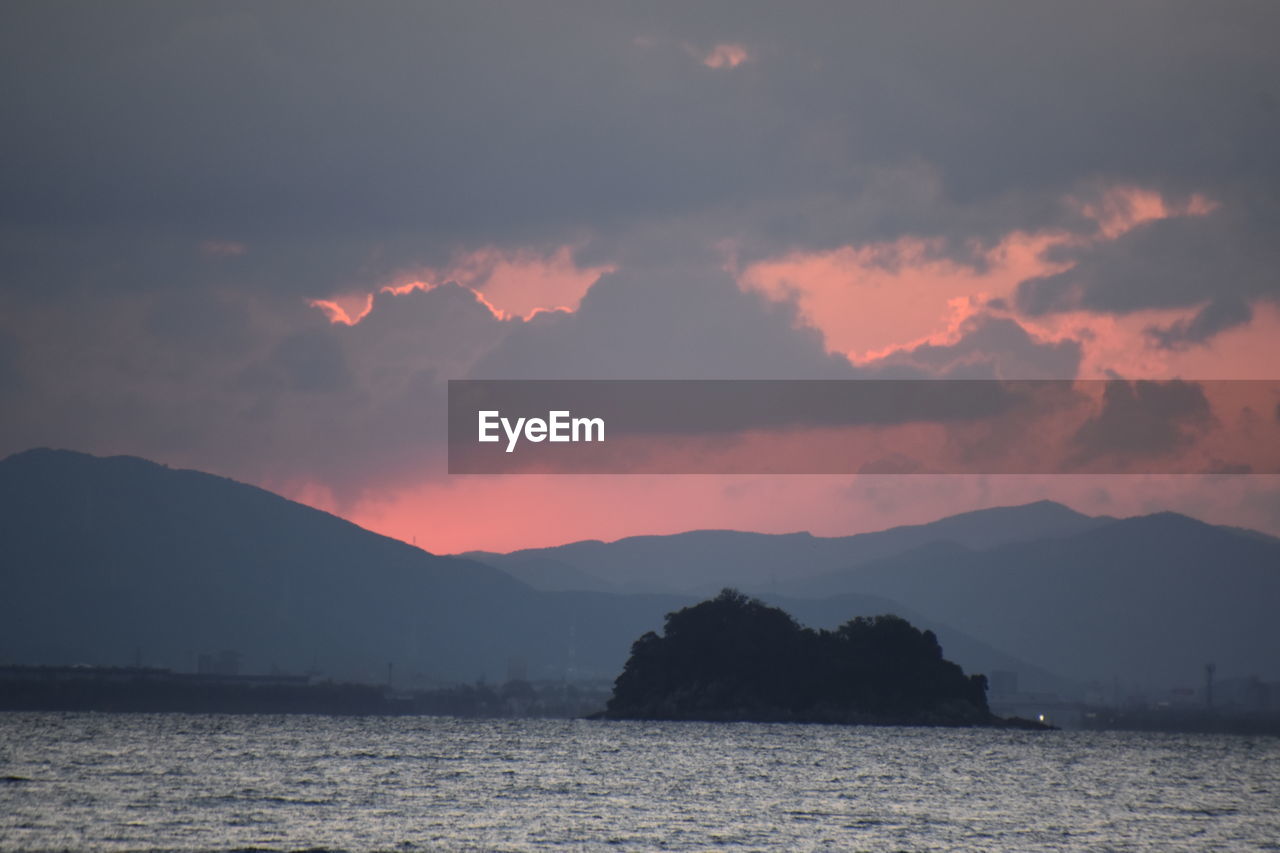 SCENIC VIEW OF SEA AND SILHOUETTE MOUNTAINS AGAINST SKY DURING SUNSET