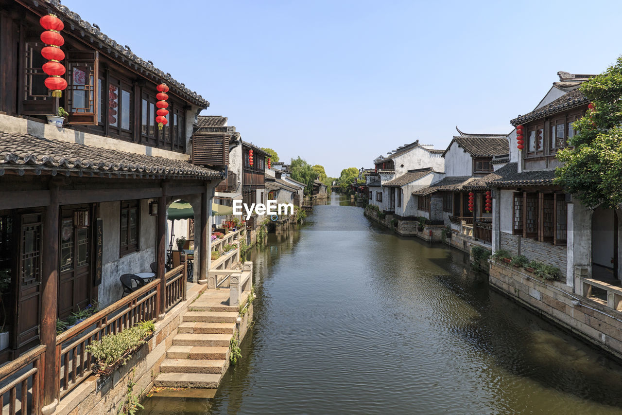 Canal amidst houses against sky in city