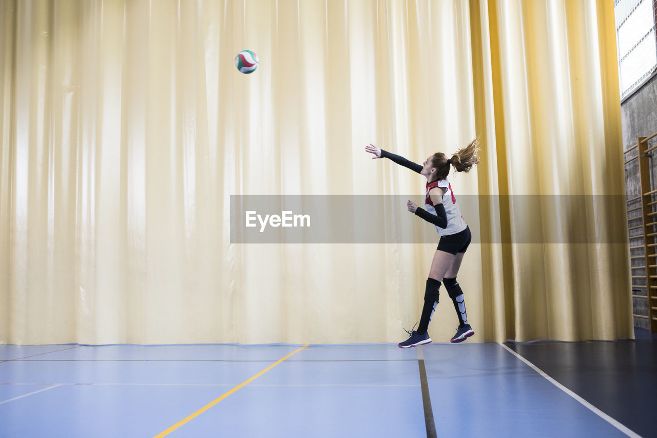 Professional female volleyball player in action serving ball