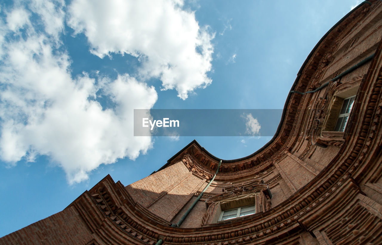 Directly below shot of building and cloudy sky on sunny day