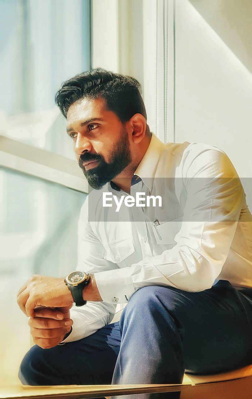 Thoughtful businessman looking through window in office