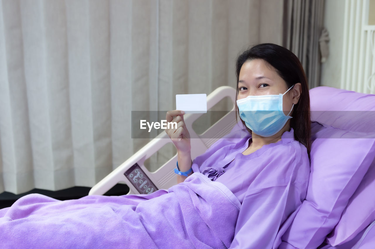 Female patient is smiling and showing blank credit card, healthcare and insurance concept.