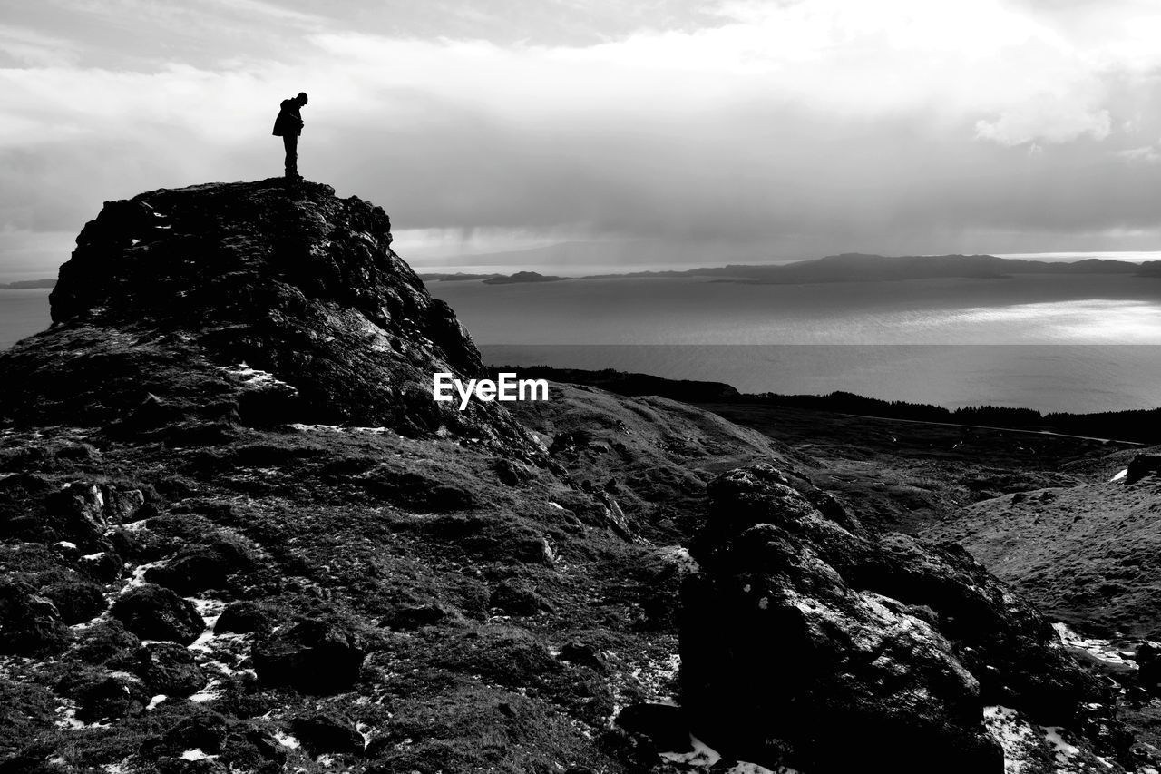 Man standing on cliff against sky