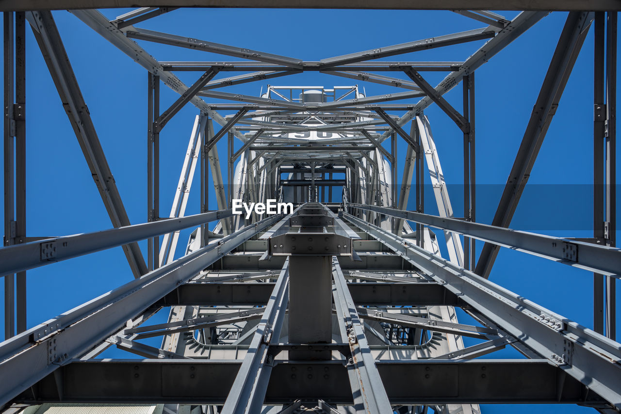 Low angle view of electricity pylon against clear blue sky