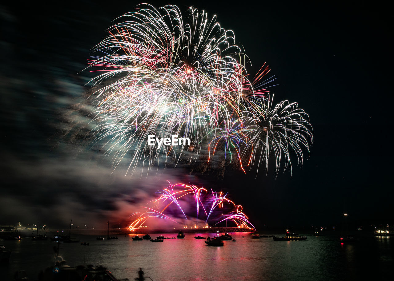 FIREWORK DISPLAY OVER RIVER AGAINST SKY