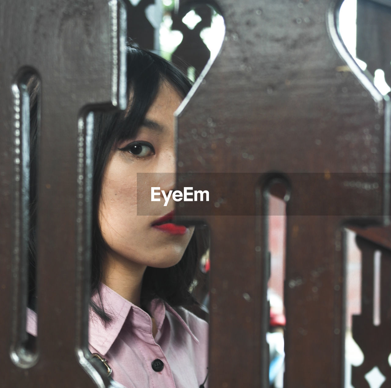 PORTRAIT OF YOUNG WOMAN LOOKING THROUGH OPEN WINDOW