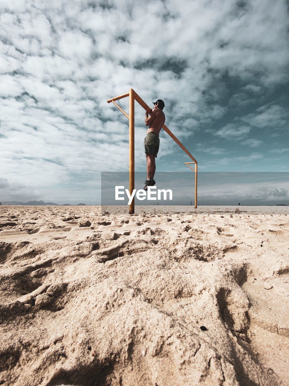 Low angle view of man exercising at beach against sky