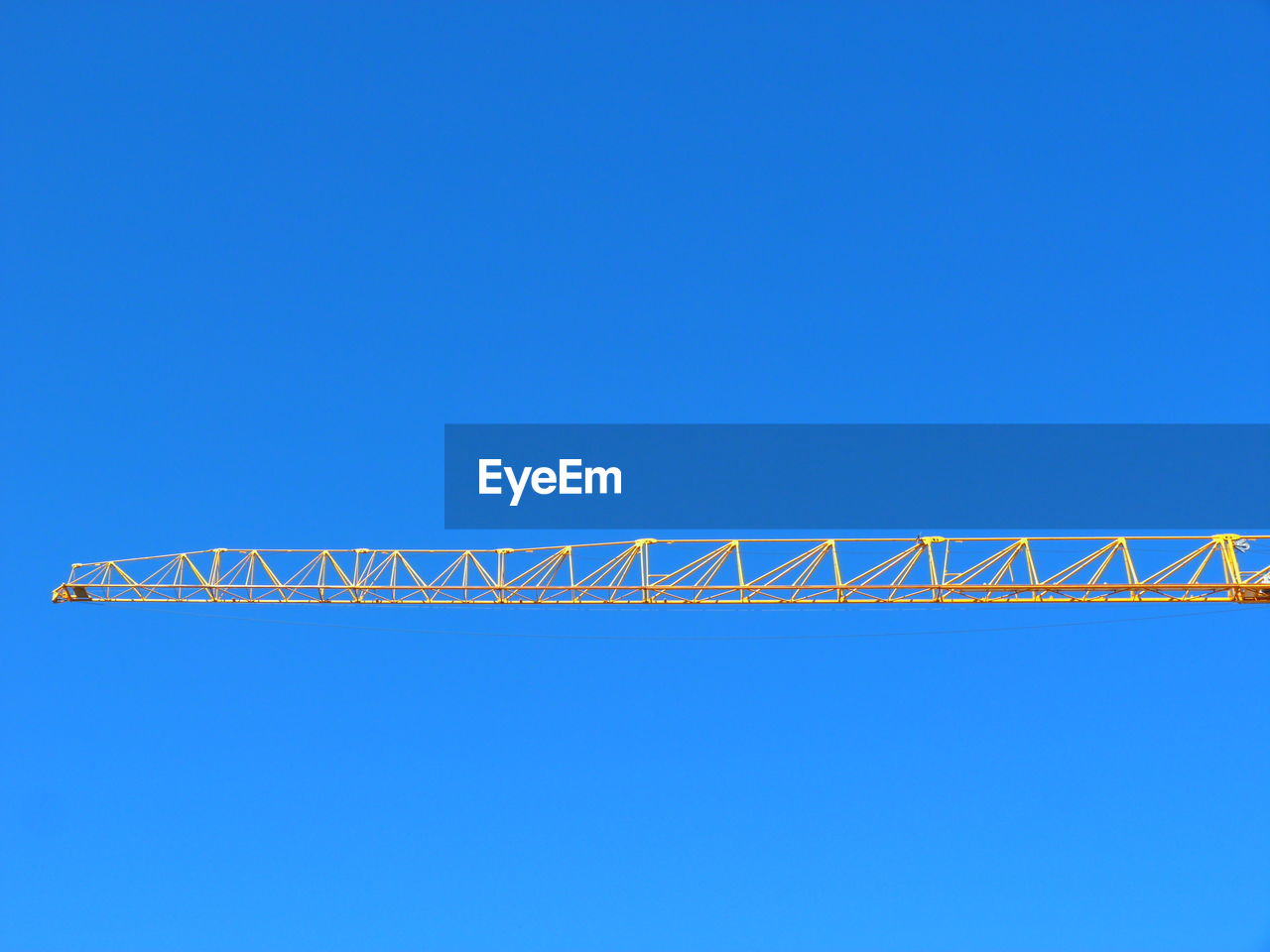 LOW ANGLE VIEW OF CRANE AGAINST BLUE SKY