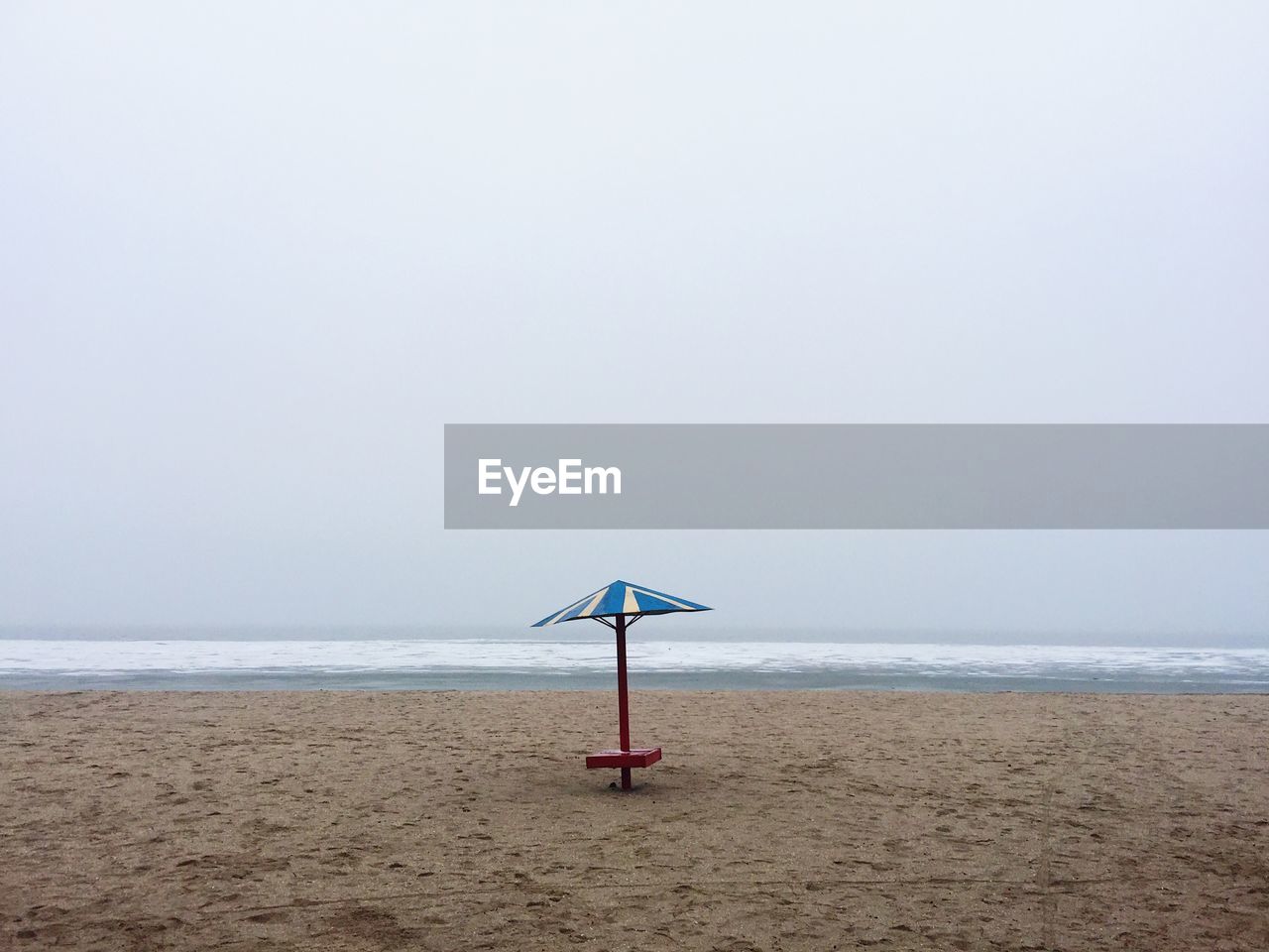 Parasol at beach against frozen sea