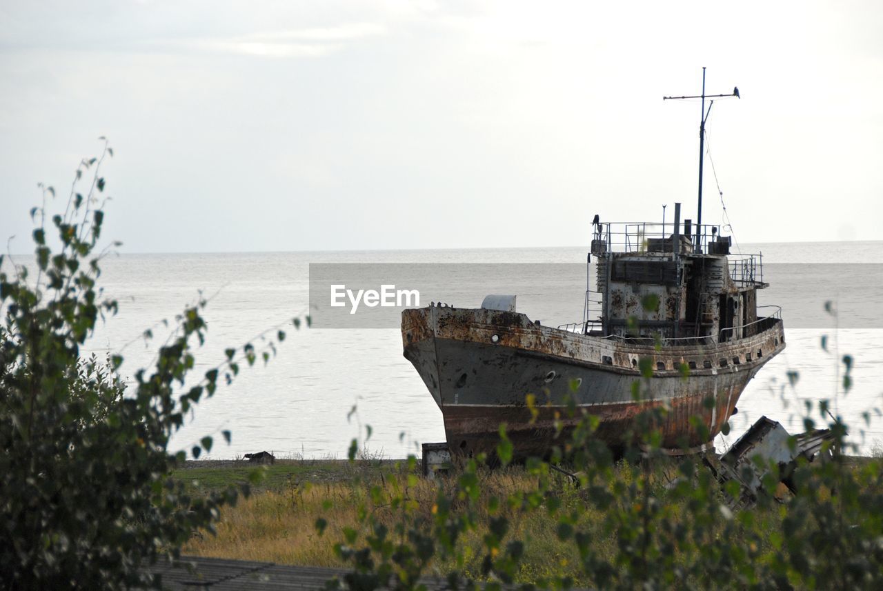 Abandoned ship moored in sea against sky