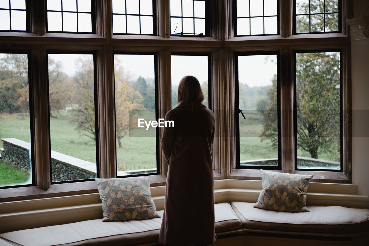 Rear view of woman looking through window