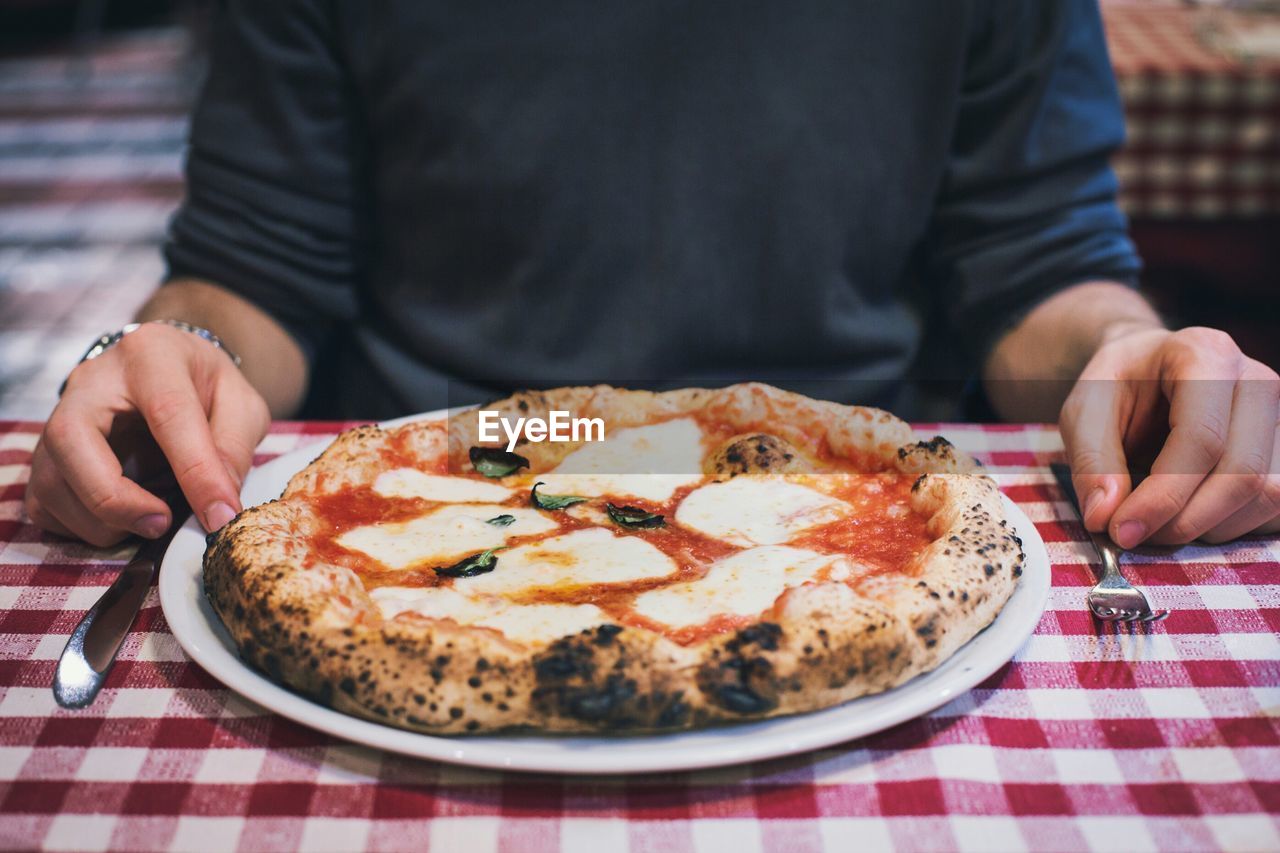 Midsection of man with pizza at table