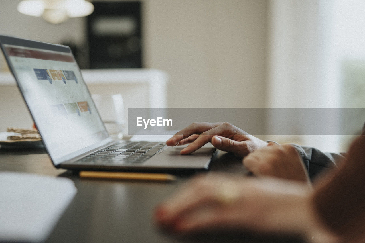 Cropped image of teenage boy using laptop at home