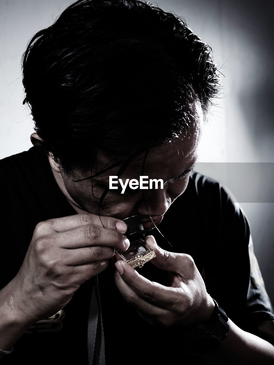 Close-up of man looking at amulet through loupe