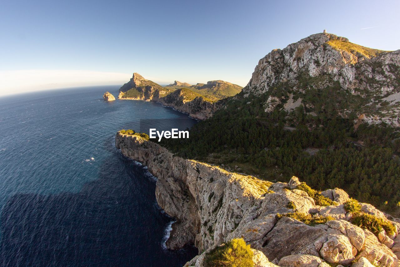 Scenic view of sea by cliff against sky