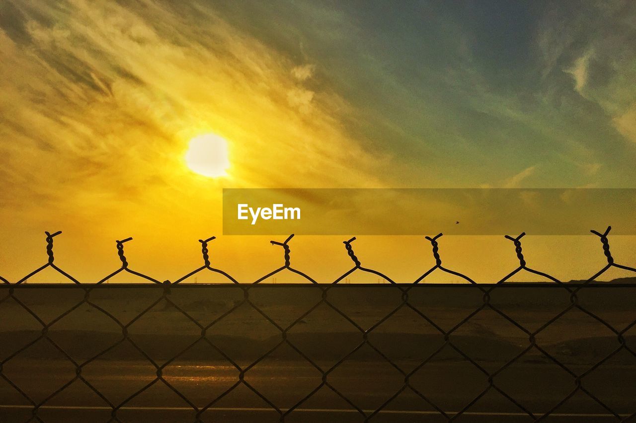 VIEW OF CHAINLINK FENCE AT SUNSET