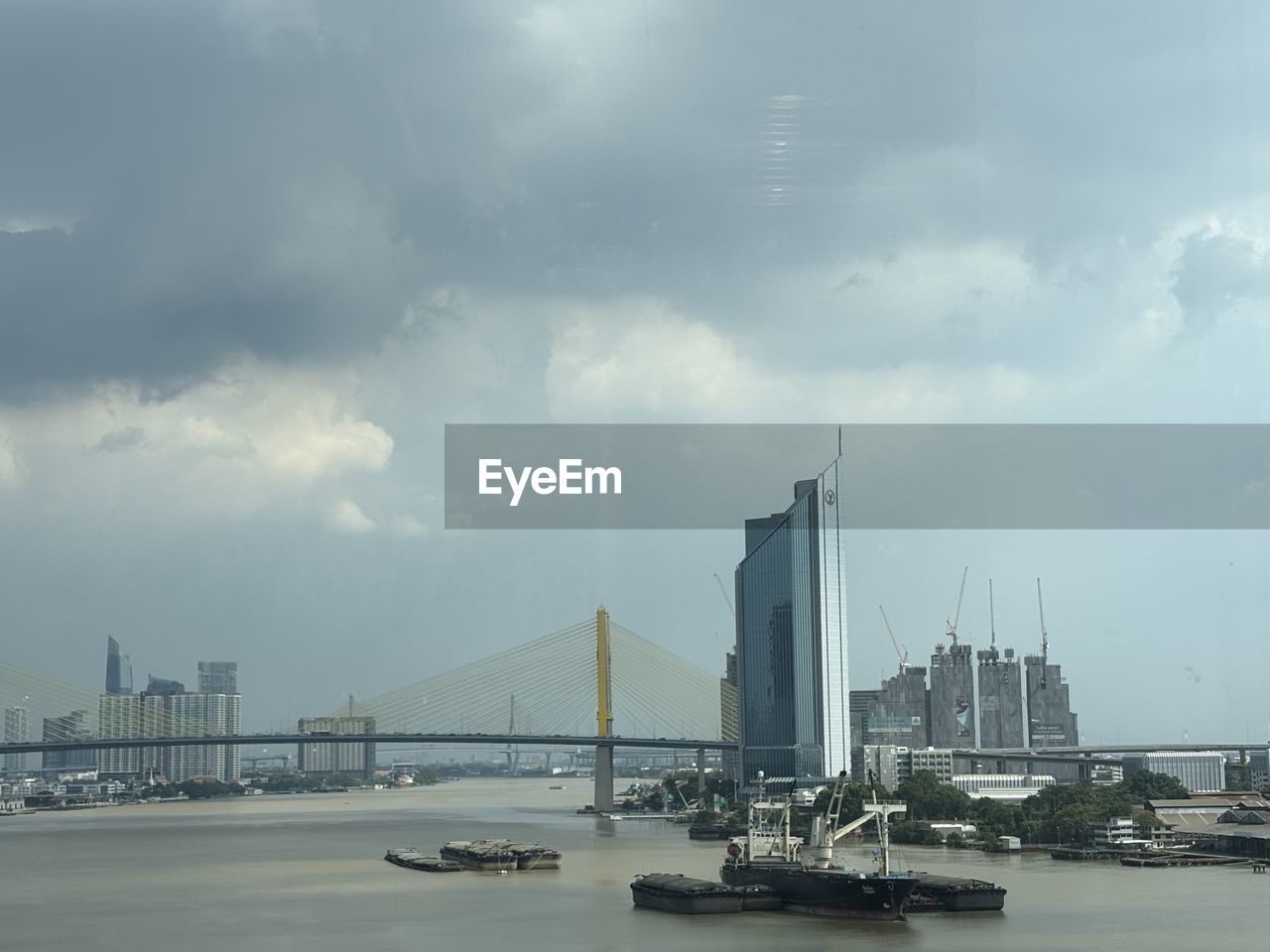architecture, sky, built structure, transportation, cloud, water, city, building exterior, nature, bridge, sea, travel destinations, nautical vessel, travel, mode of transportation, building, no people, cityscape, skyline, landscape, vehicle, outdoors, urban skyline, horizon, office building exterior, tourism, skyscraper, day, ship, harbor, sailboat, city life, bay, environment, fog, boat, overcast, suspension bridge, business
