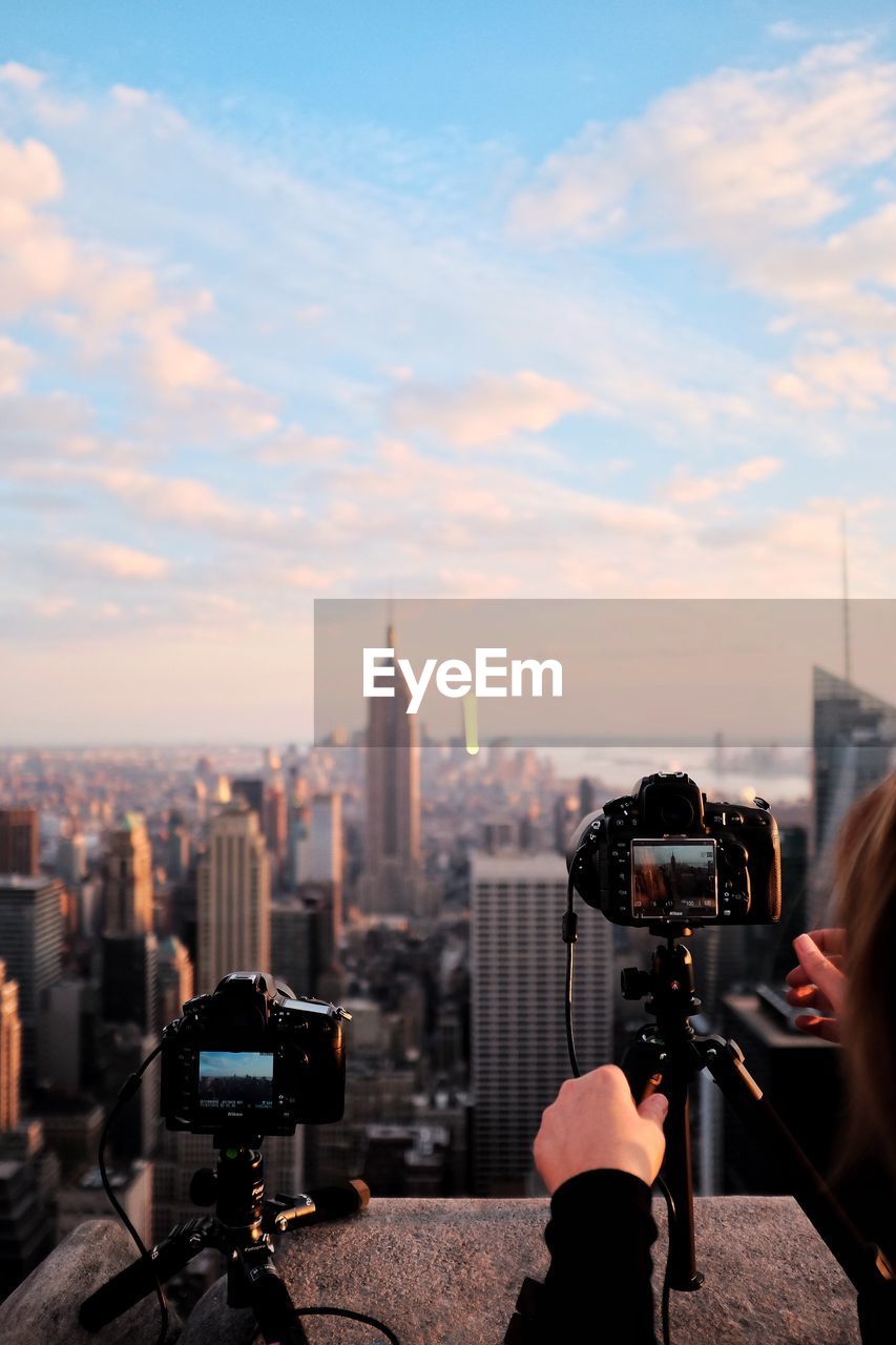 Close-up of woman photographing cityscape against sky