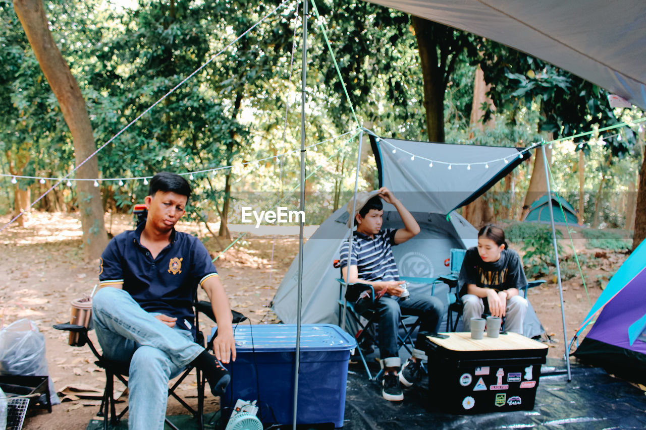 PEOPLE SITTING ON TABLE BY TREES