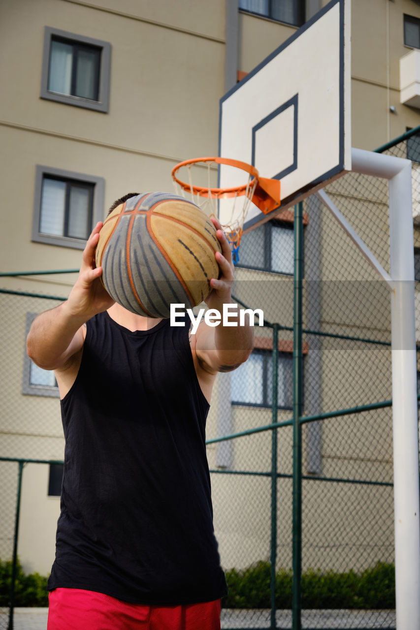 Young adult man plays basketball at outdoor court. basketball player shows his dribbling skill