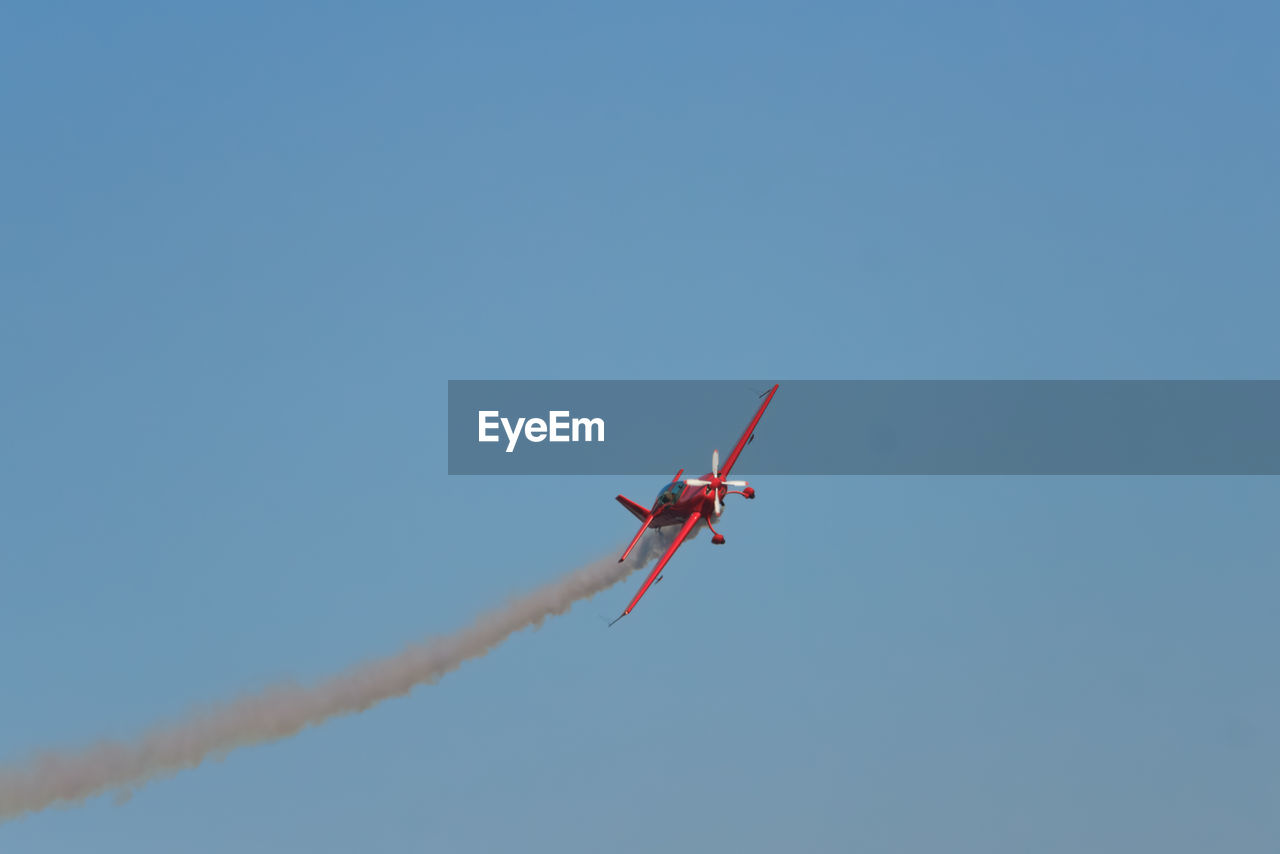 flying, air vehicle, airplane, sky, transportation, mode of transportation, on the move, air show, blue, clear sky, nature, aerobatics, motion, low angle view, no people, general aviation, day, vapor trail, smoke, mid-air, sunny, copy space, outdoors, aviation, cloud, vehicle, aircraft, wing, teamwork, travel, event, red, cooperation, performance