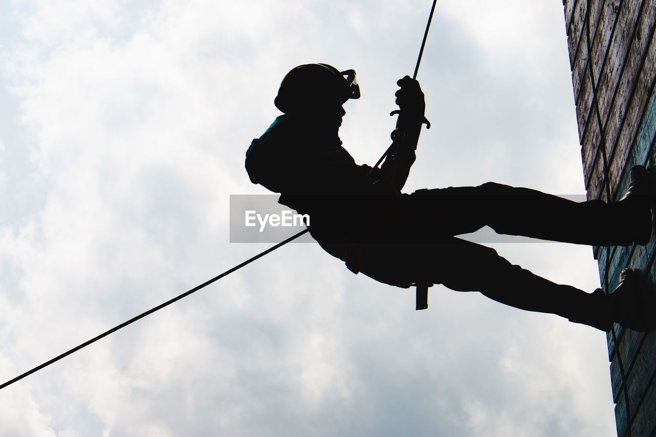 SILHOUETTE MAN HOLDING ROPE AGAINST SKY