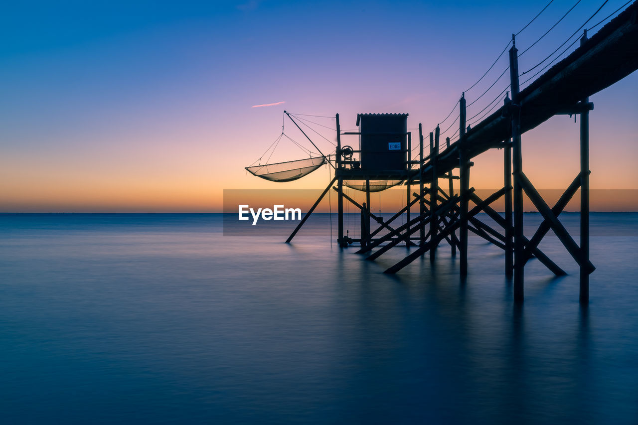 Typical  wooden fishing huts on stilts called carrelet  in the atlantic ocean near at sunset