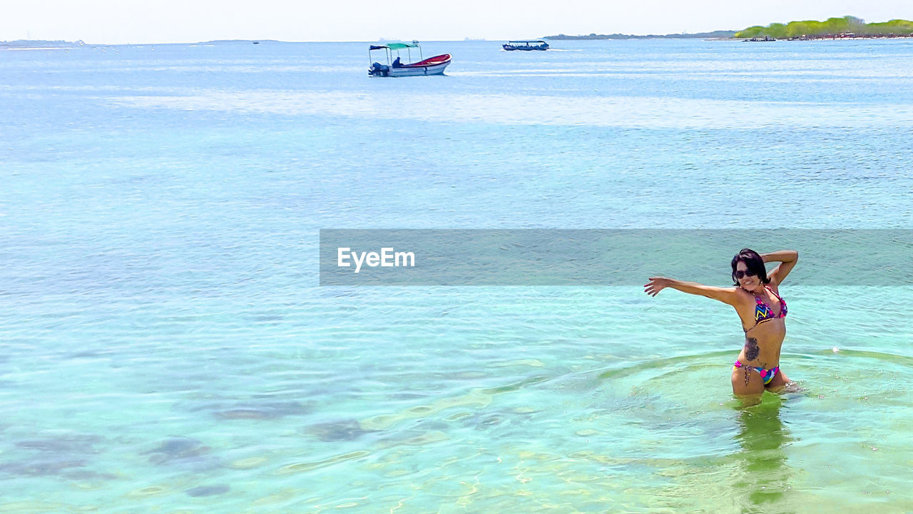 Happy woman posing on sea during sunny day