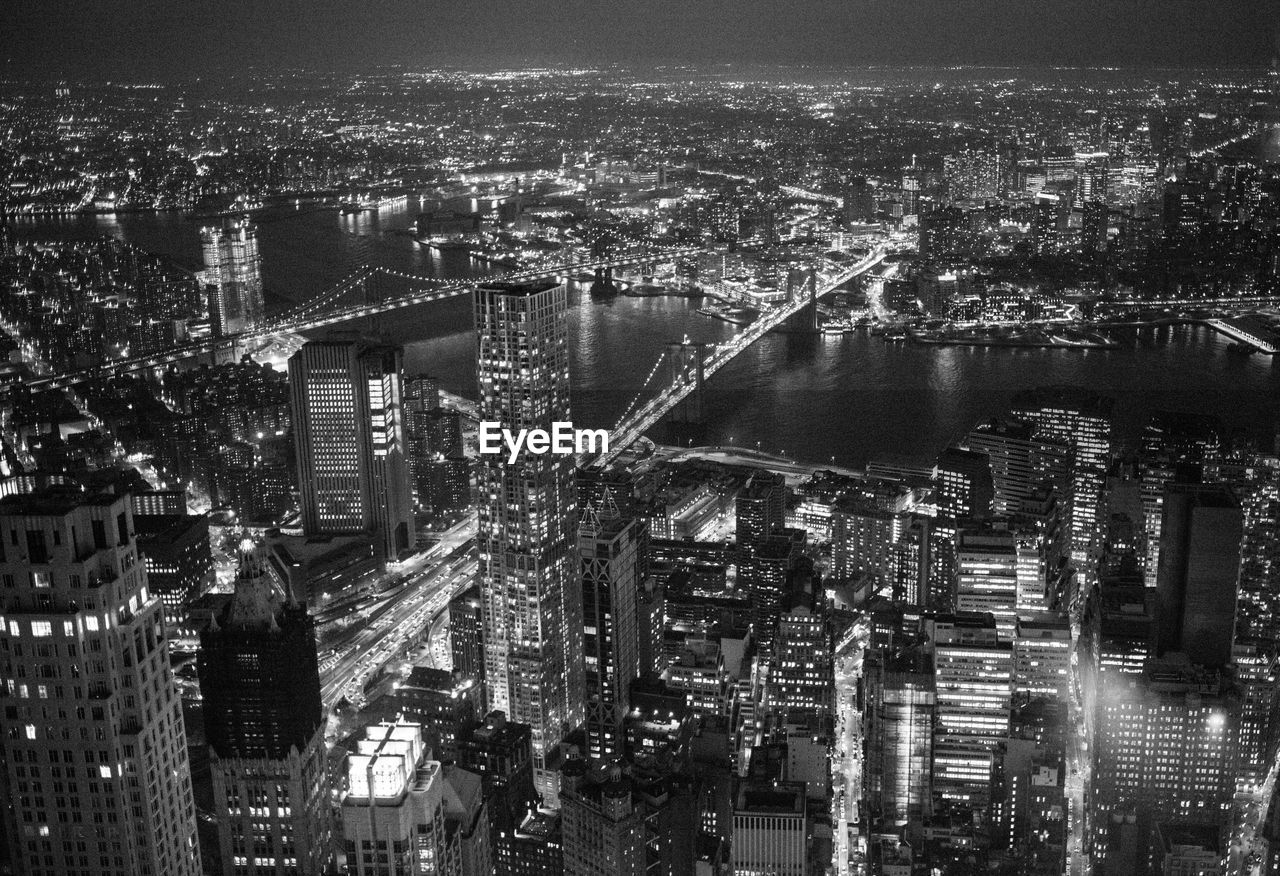 High angle view of illuminated city by river and buildings